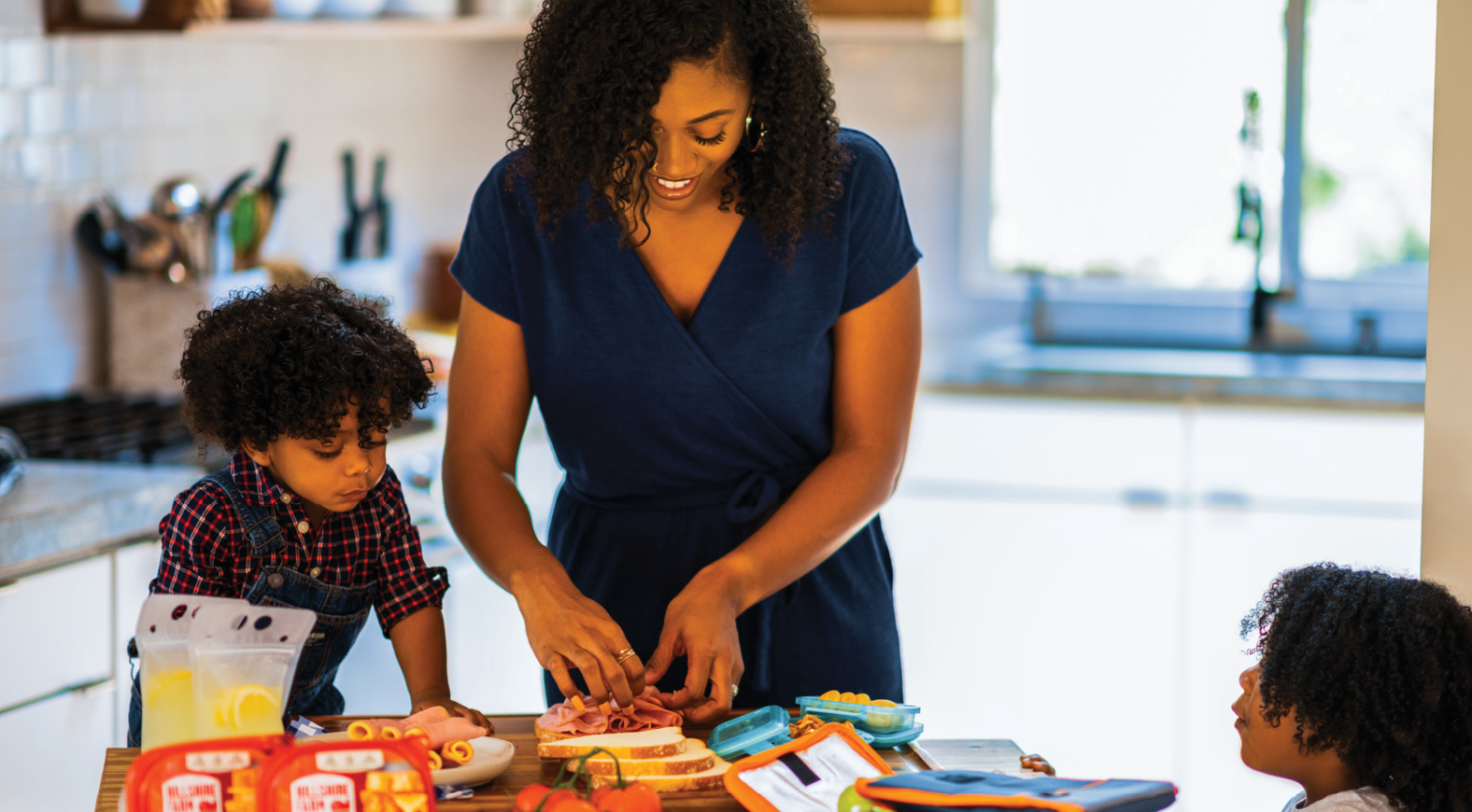 mom prepares food in her kitchen with 2 toddlers at a table